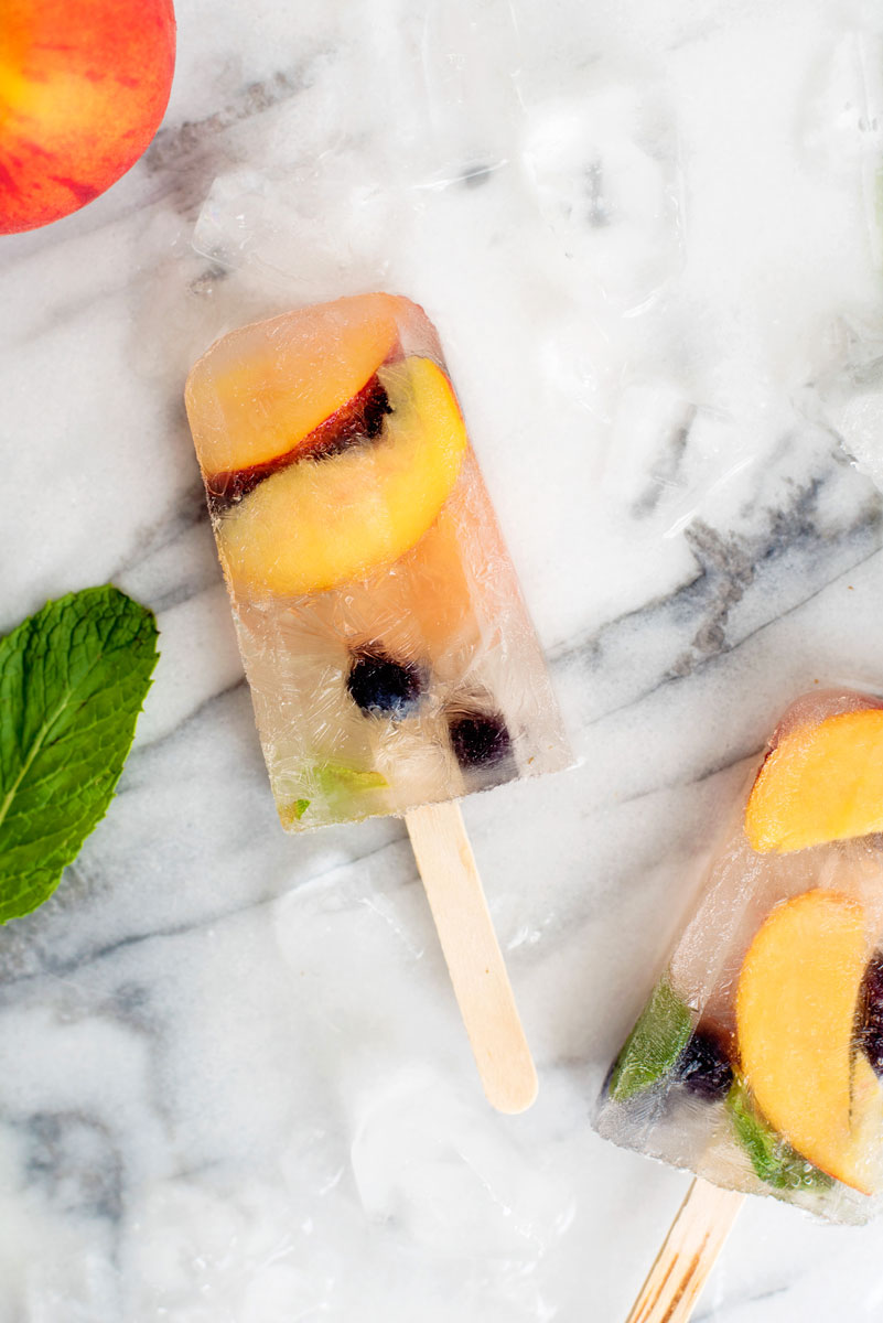 Boozy Peach Sangria Popsicles Served in Prosecco Recipe - perfect to beat the summer heat!