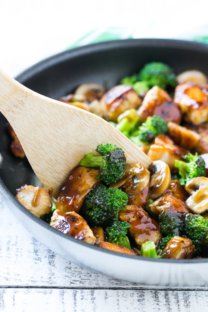 A spatula scooping chicken and broccoli stir fry out of a pan.