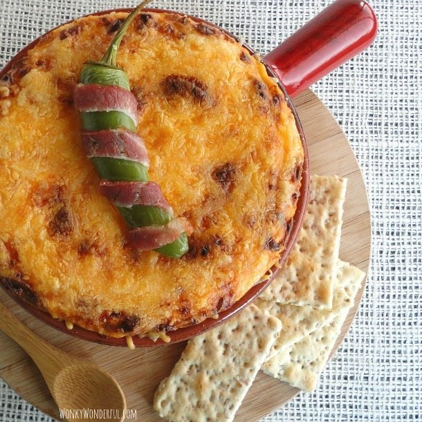 jalapeno popper dip ina red ceramic dish with crackers on the side